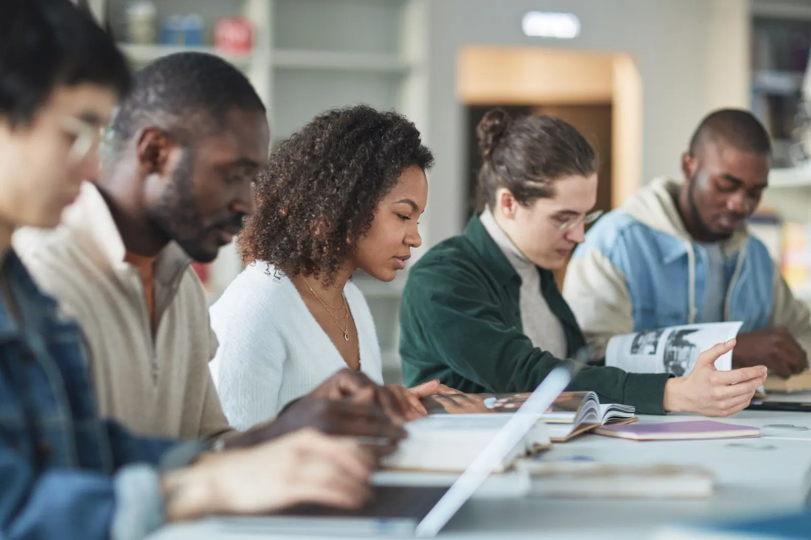 Étudiants de profils variés qui révisent ensemble à une table de bibliothèque
