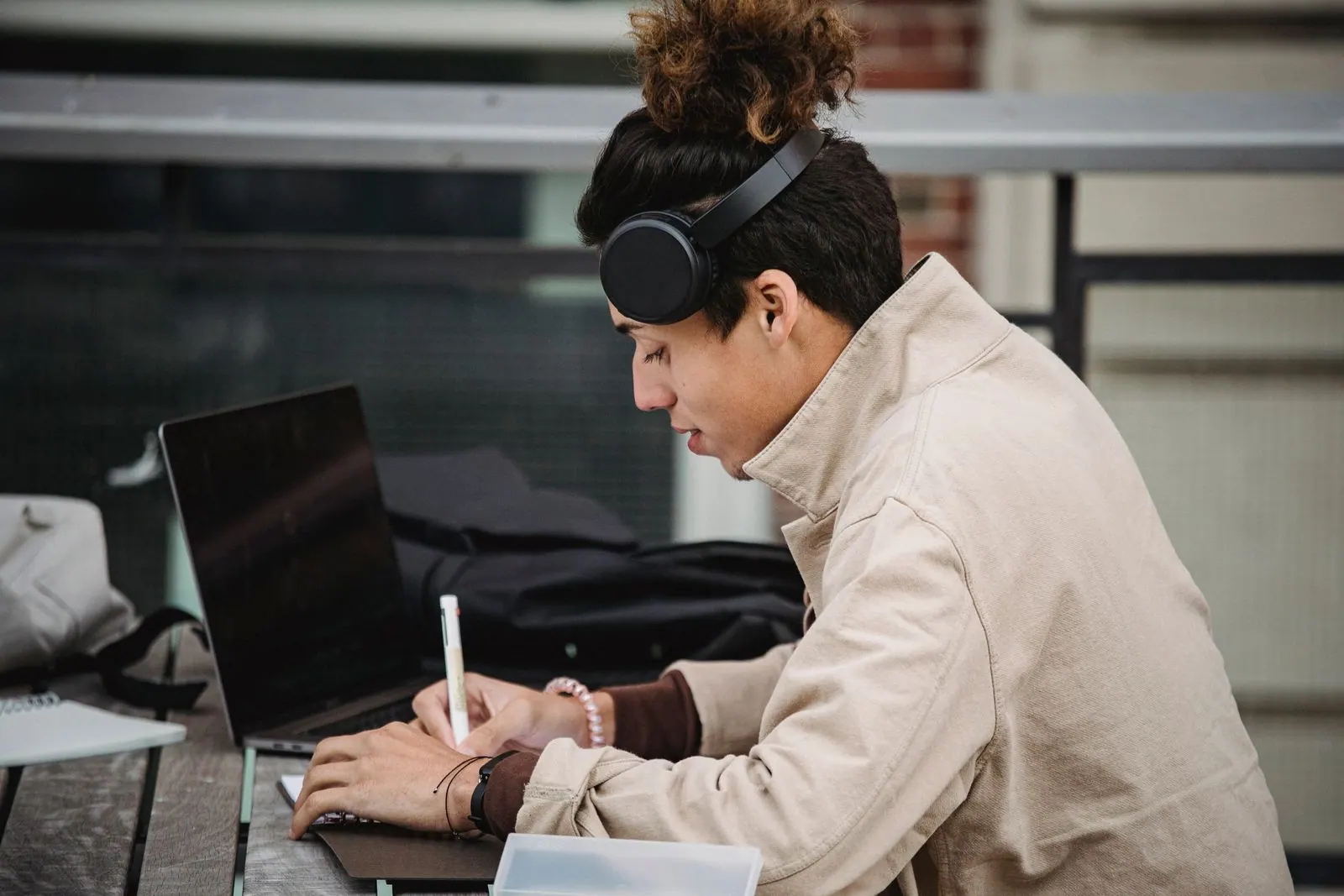 Étudiant avec un casque audio prenant des notes devant son ordinateur